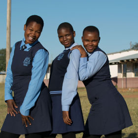 Three Girls from Swaziland pose in front of their school. Photo by Rebecca Sliwoski.