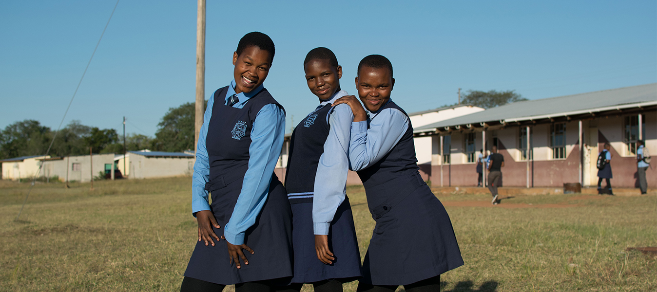 Three Girls from Swaziland pose in front of their school. Photo by Rebecca Sliwoski.