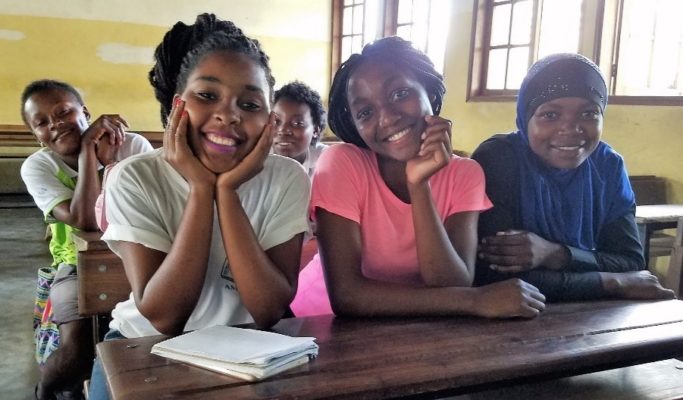 Hawambo sits and smiles with the girls she mentors as a DREAMS Mentor in Mozambique.